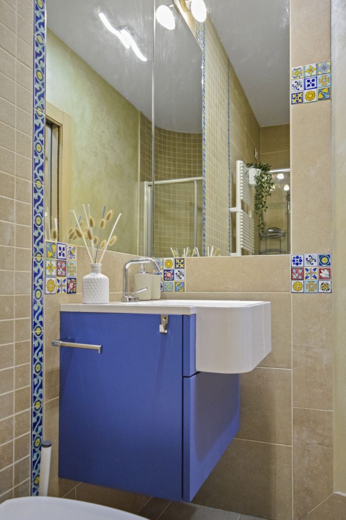 Bagno elegante con mosaici caratteristici, lavabo moderno, ampia doccia e sanitari bianchi.