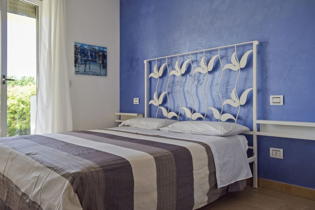 Camera matrimoniale luminosa con letto matrimoniale, arredamento elegante e moderno.