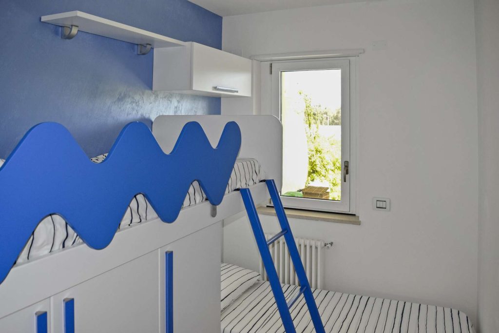 Stanza singola con due letti, uno a soppalco, arredata in stile moderno e accogliente.