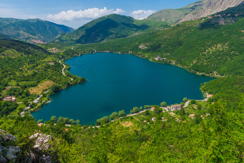 Veduta panoramica del Lago di Scanno circondato da montagne e vegetazione.